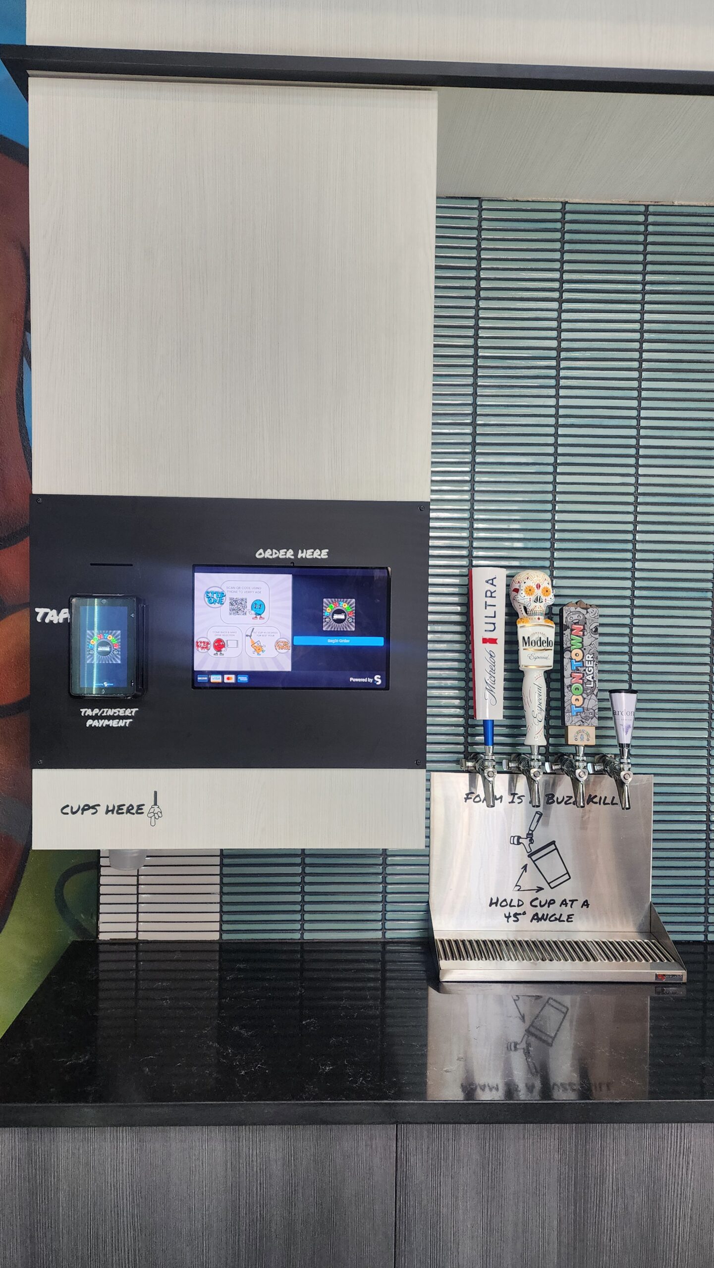 Unattended self-service TendedBar beverage station with order-here touchscreen and cup dispenser, no staff present